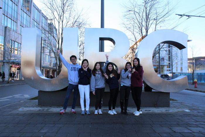 學生在不列顛哥倫比亞大學牌匾前微笑