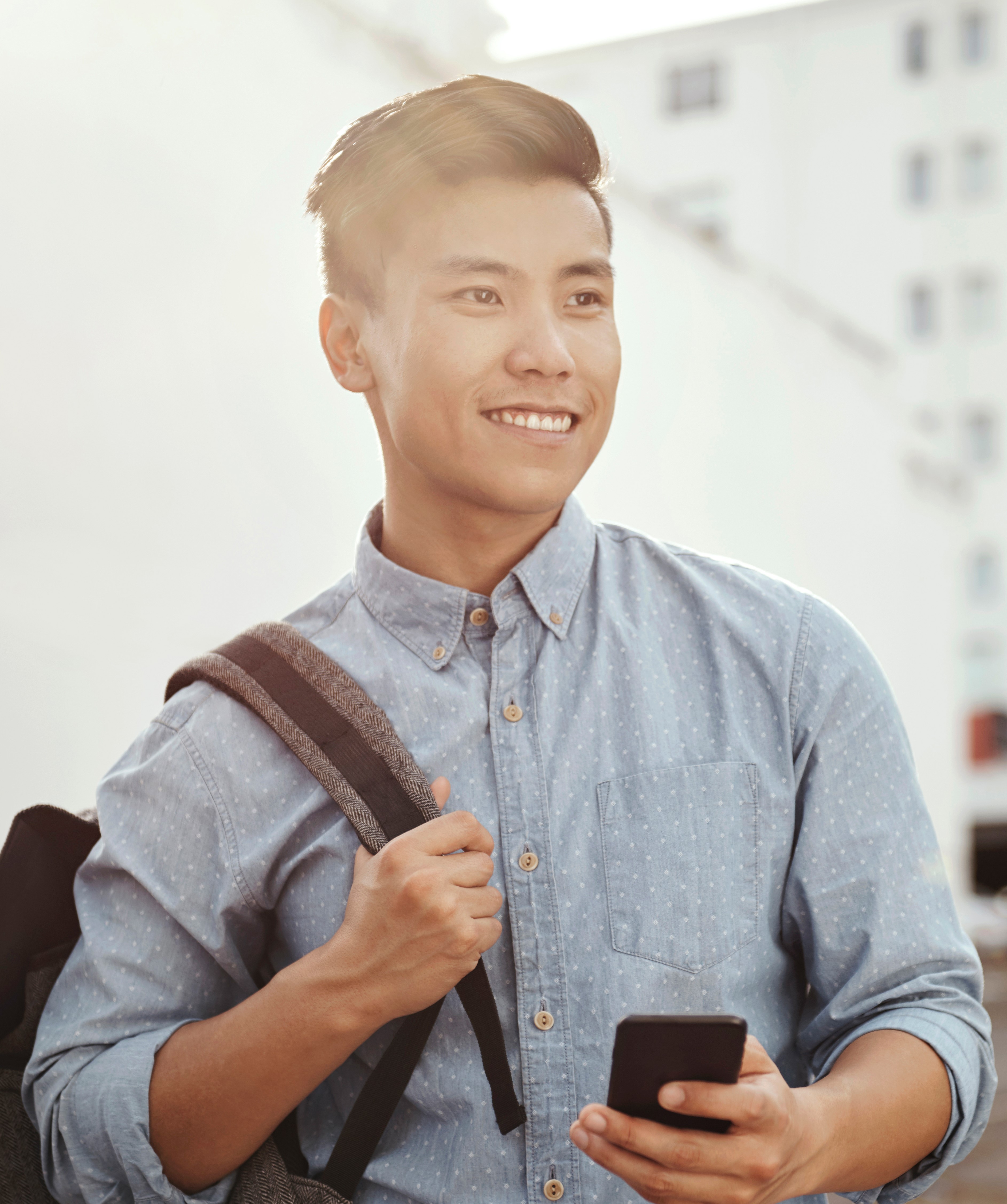 Male student smiling with phone in hand