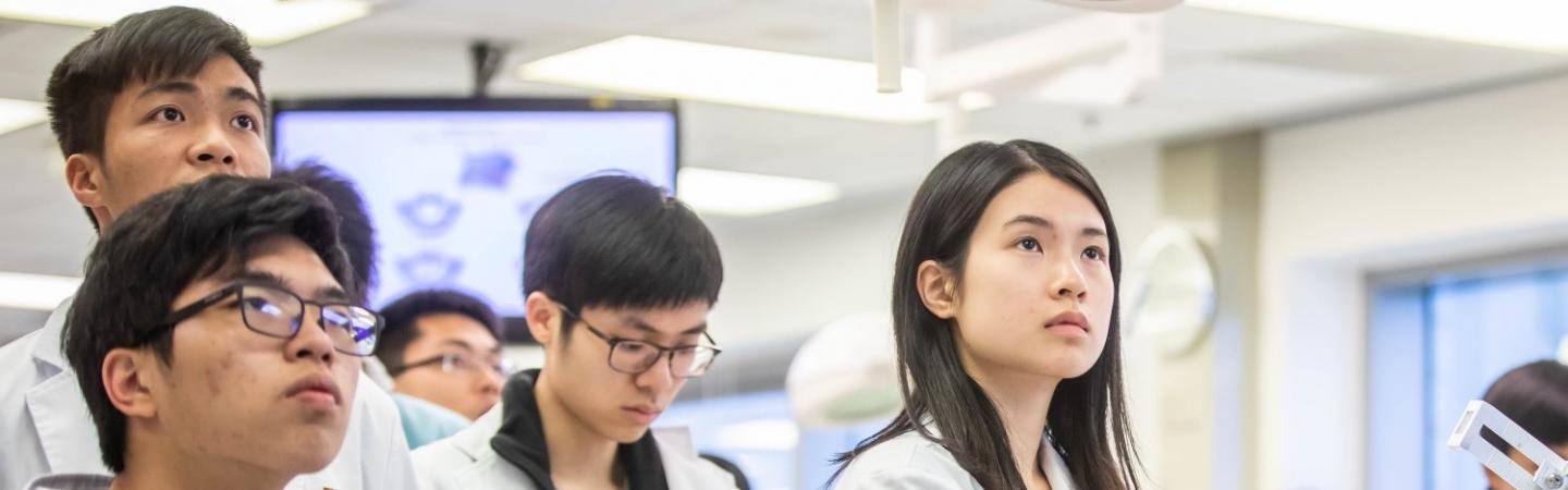 Students wearing white gown looking focused