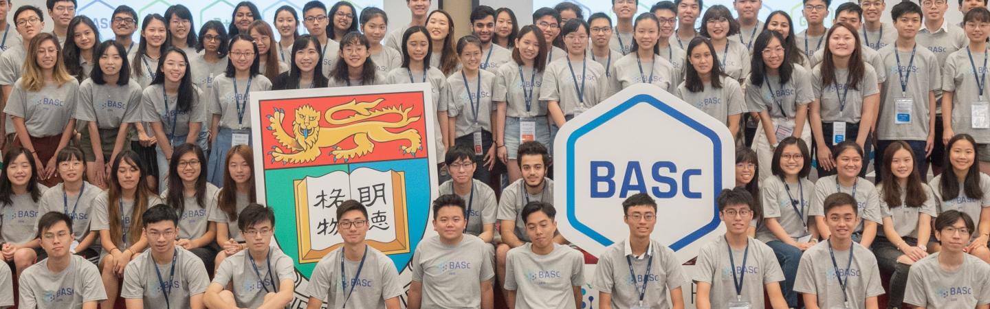 Design+Students sitting in front or standing behind three signs showing HKU crest, GHD, and BASC