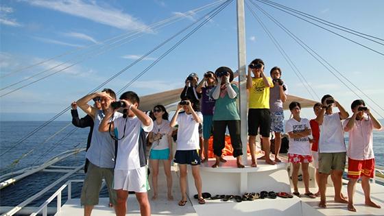 Students on a bot with binoculars