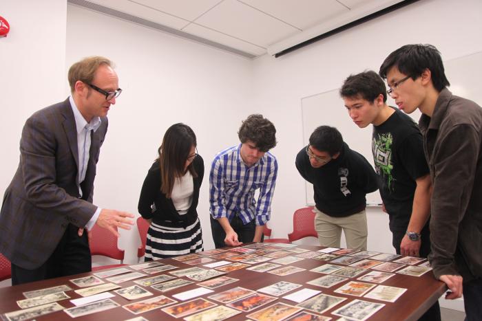 Students and professor discussing about artwork on table