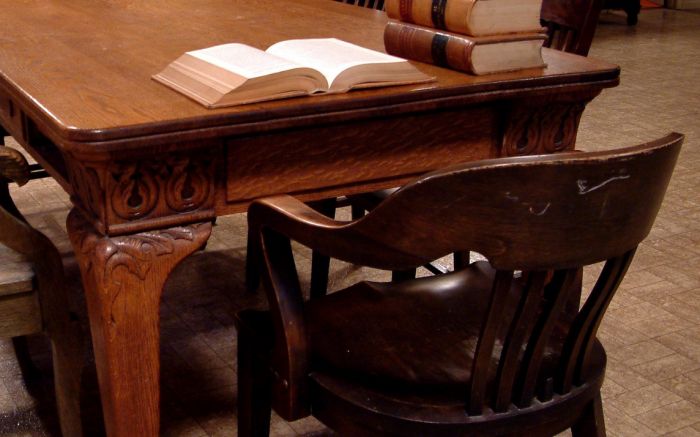 Wooden chair behind a wooden table with a book open