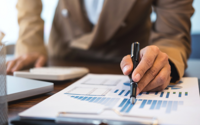 Person pointing at a bar chart with a pen