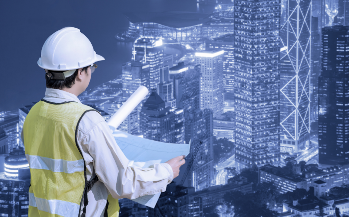 Construction engineer checking construction drawing with modern cityscape view for new Infrastructure construction project concept