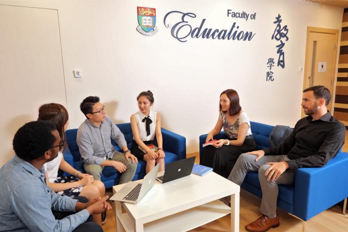 Different nationalities people are sitting in front of the plaque of Faculty of Education