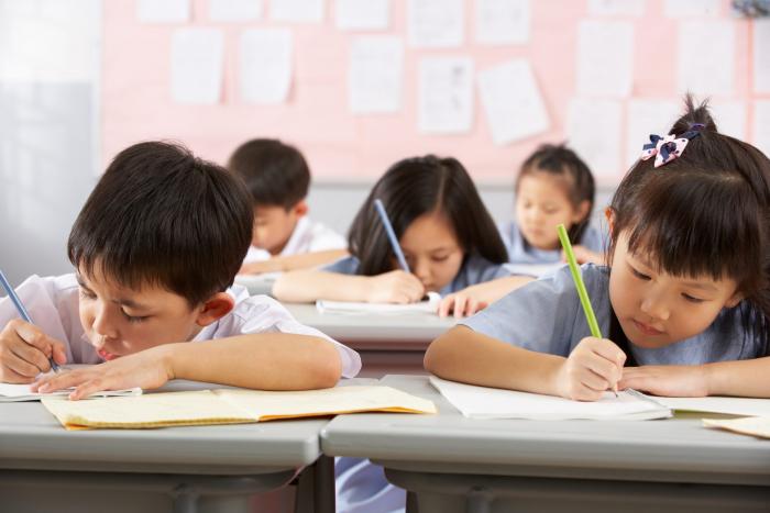 Primary students are writing on their textbooks