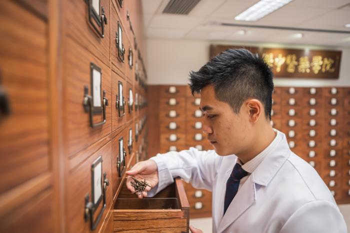 穿着医用长袍的学生在架上浏览药品