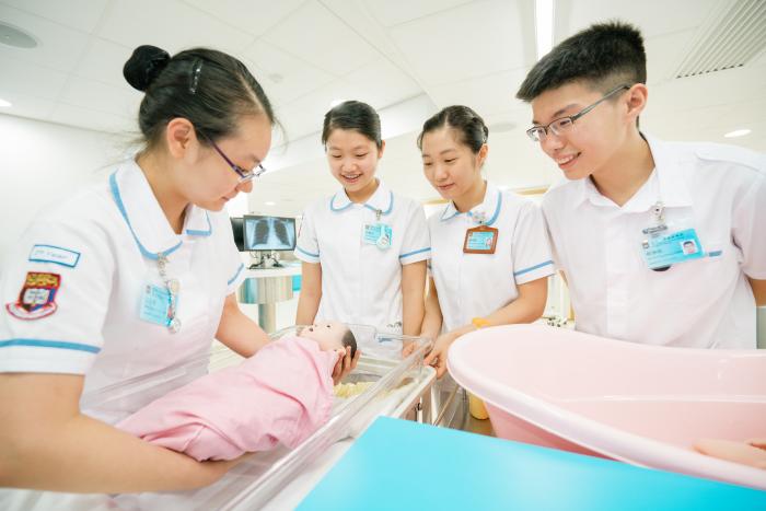 Students wearing nurse uniform holding a baby doll