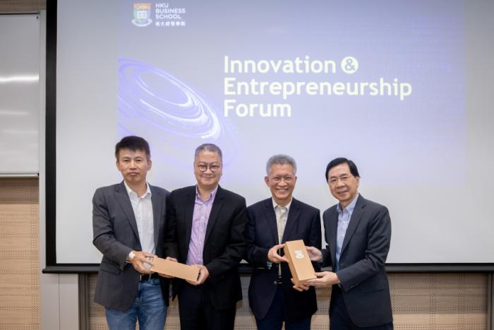 Professors and speakers holding souvenirs in front of screen "Innovation & Entrepreneurship Forum"