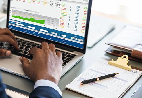 Zoom in on hands working on computer showing stock market