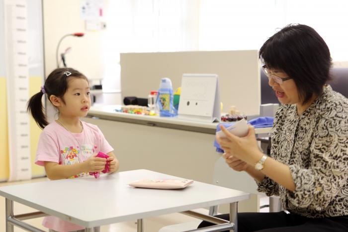 A lady is talking to a little girl while holding some cards