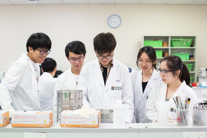 Students wearing white gown looking focused