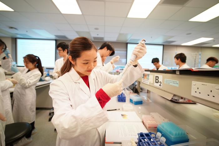 Students wearing lab coat working with equipment in lab