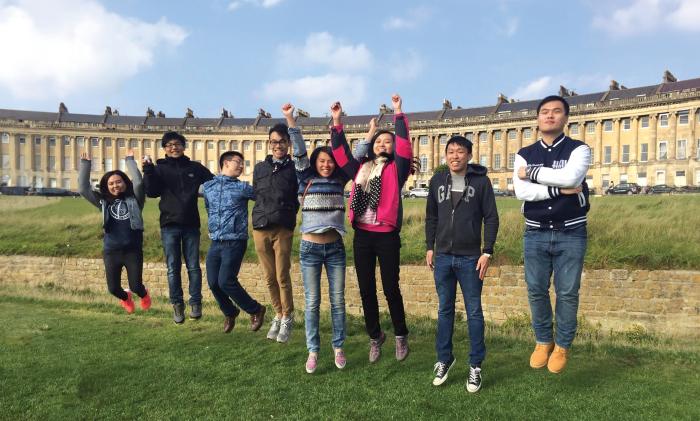 学生在白板前工作，桌上有笔记本计算机和地球仪