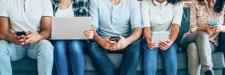 people sitting down while looking at phone or laptop