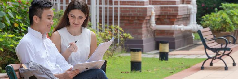 Students conversing and looking at laptop on campus